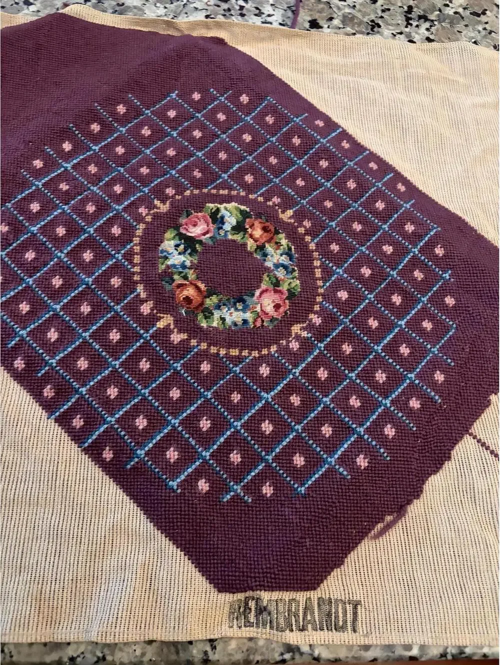 needlepoint tapestry featuring a wreath and geometric pattern.